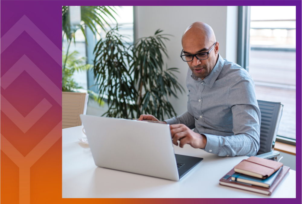 A person sitting at a desk looking at a laptop