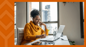 A person sitting at a desk looking at a laptop
