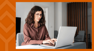 A person sitting at a desk looking at a laptop