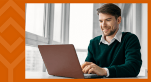 A person sitting at a desk looking at a laptop