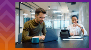 Two people sitting at a table with a laptop