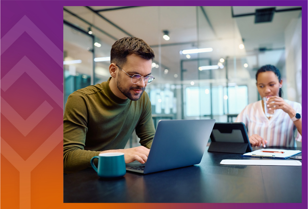 Two people sitting at a table with a laptop