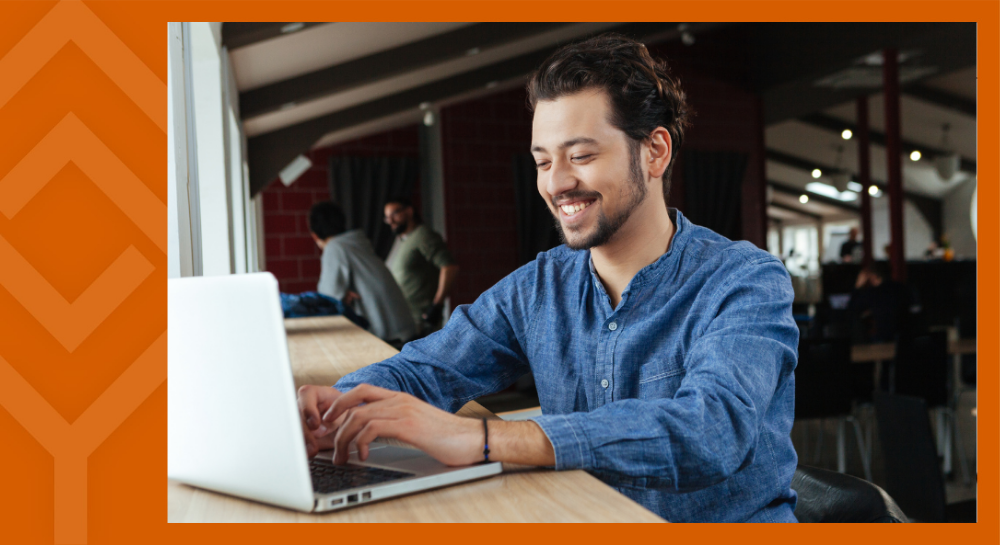 A person sitting at a desk looking at a laptop
