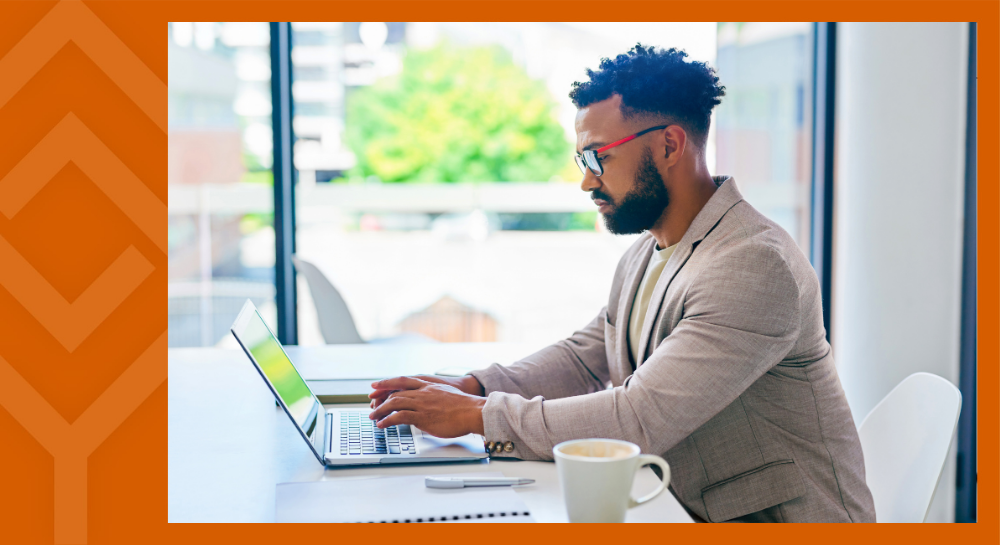 A person sitting at a desk looking at a laptop