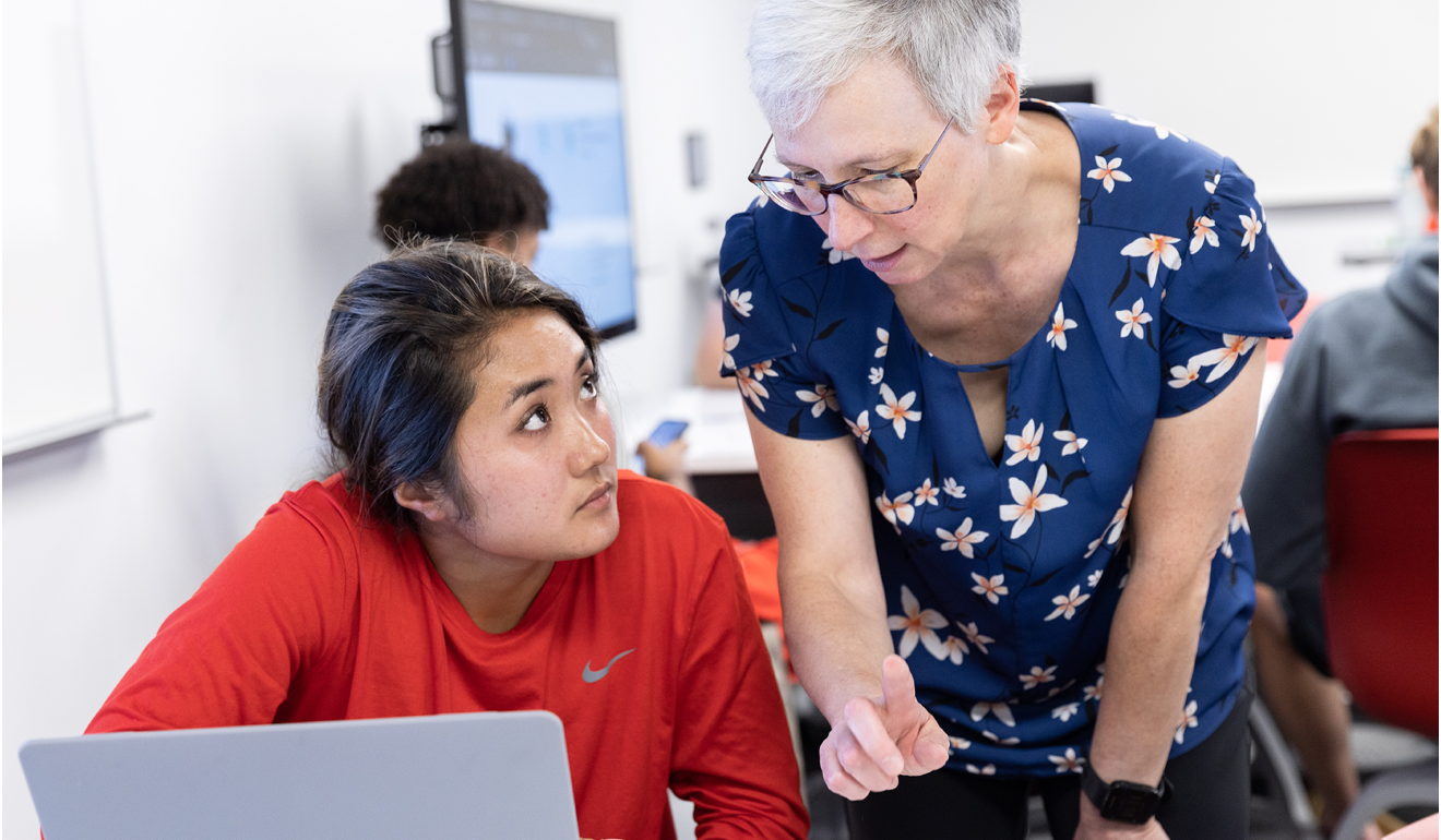 Two people talking in front of a laptop