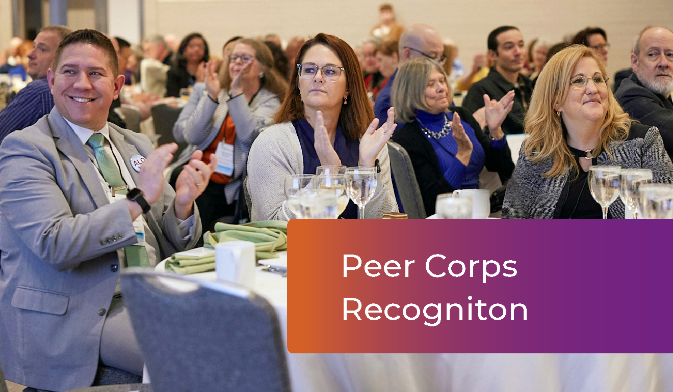 People sitting around a table clapping at the HLC Annual Conference, "Peer Corps Recognition"